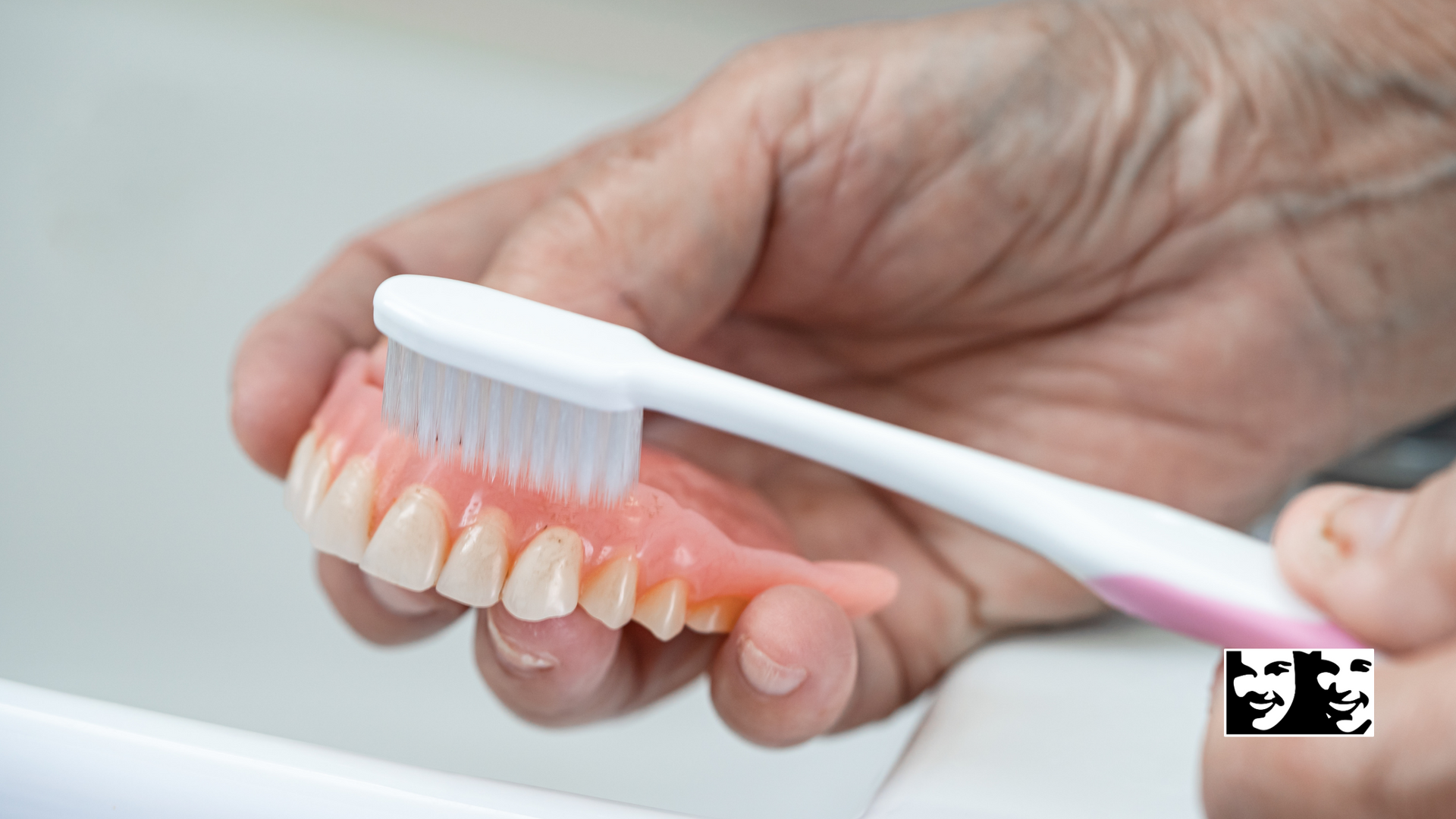 A person is brushing their dentures with a toothbrush.