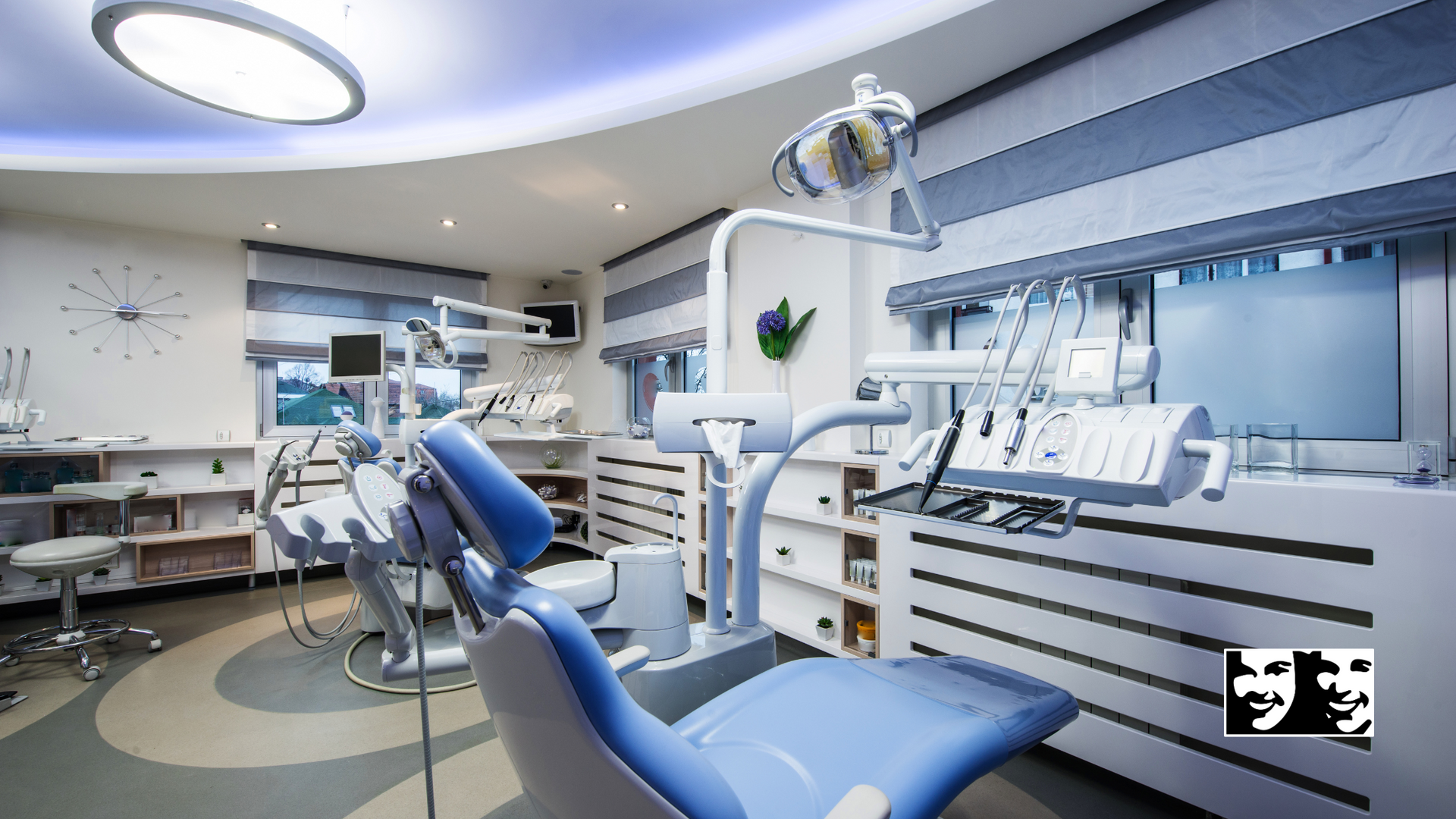 A dental office with a blue chair and a clock on the wall