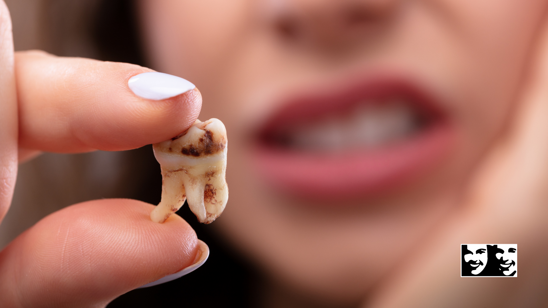 A woman is holding a tooth in her hand in front of her mouth.