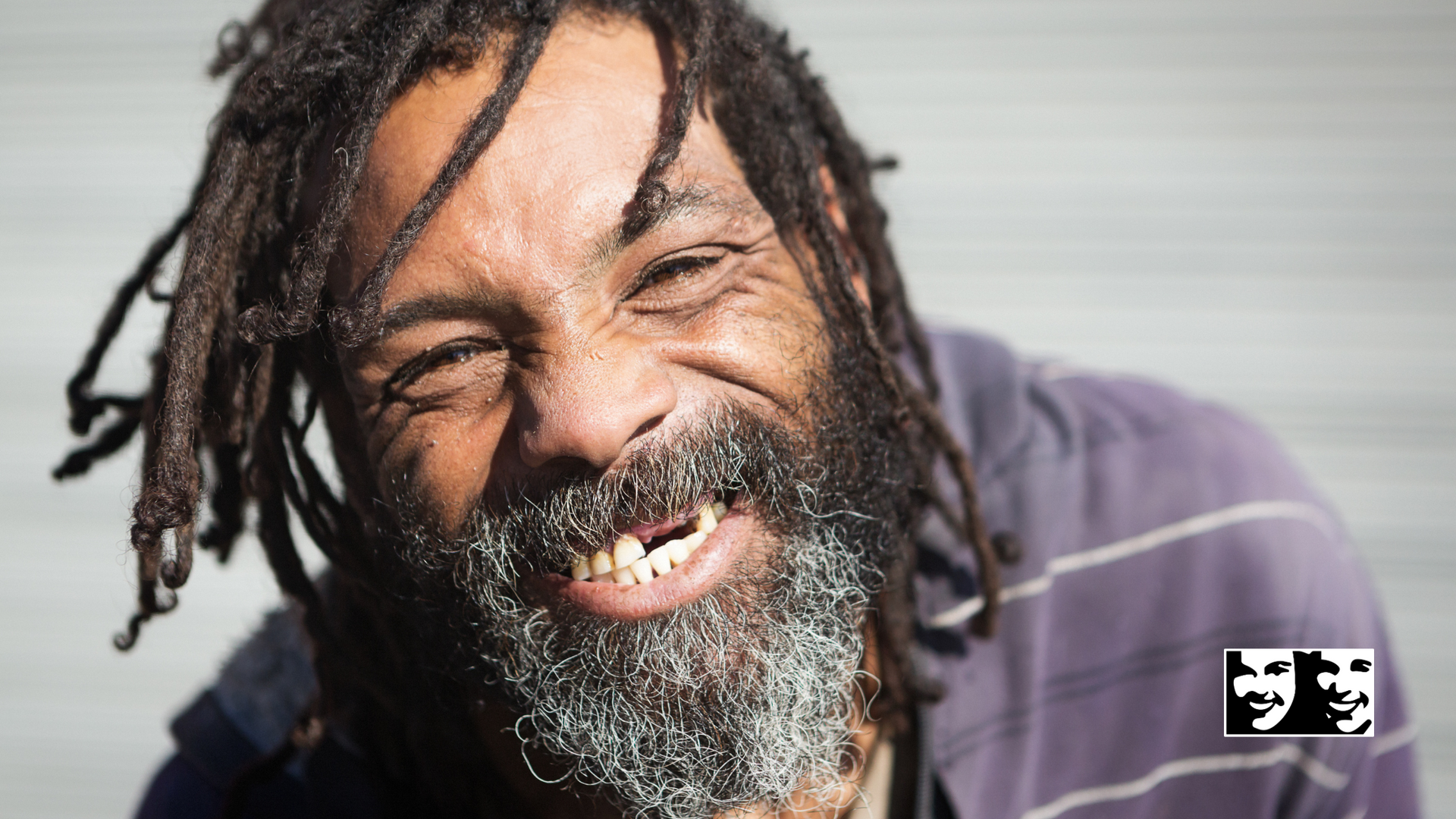 A man with dreadlocks and a beard is smiling