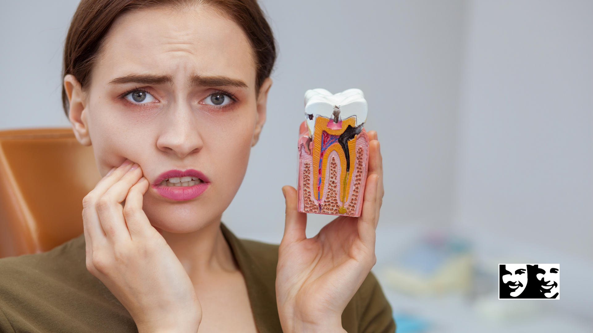 A woman is holding a model of a tooth with a toothache.