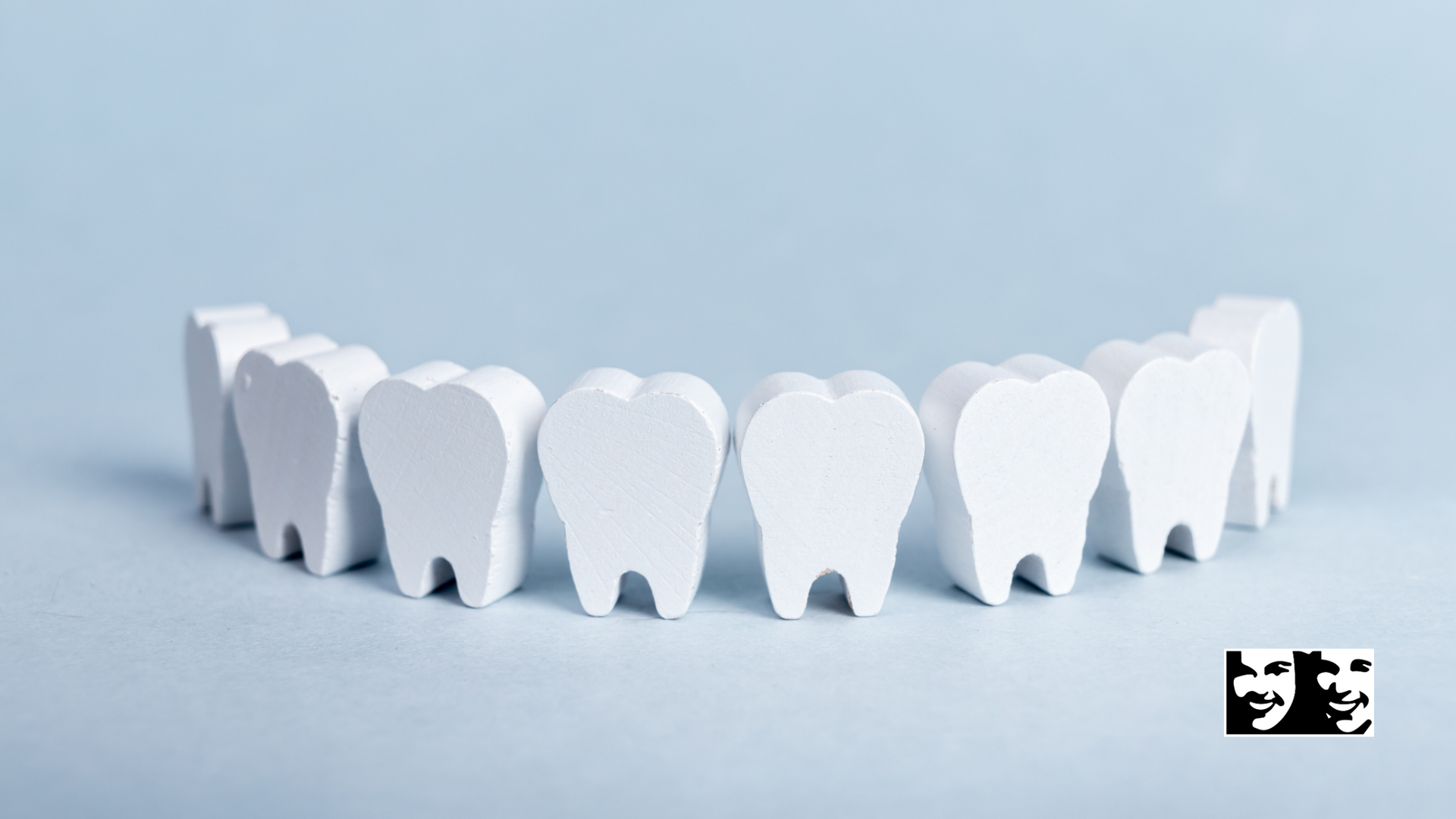 A row of white teeth are lined up in a row on a blue background.