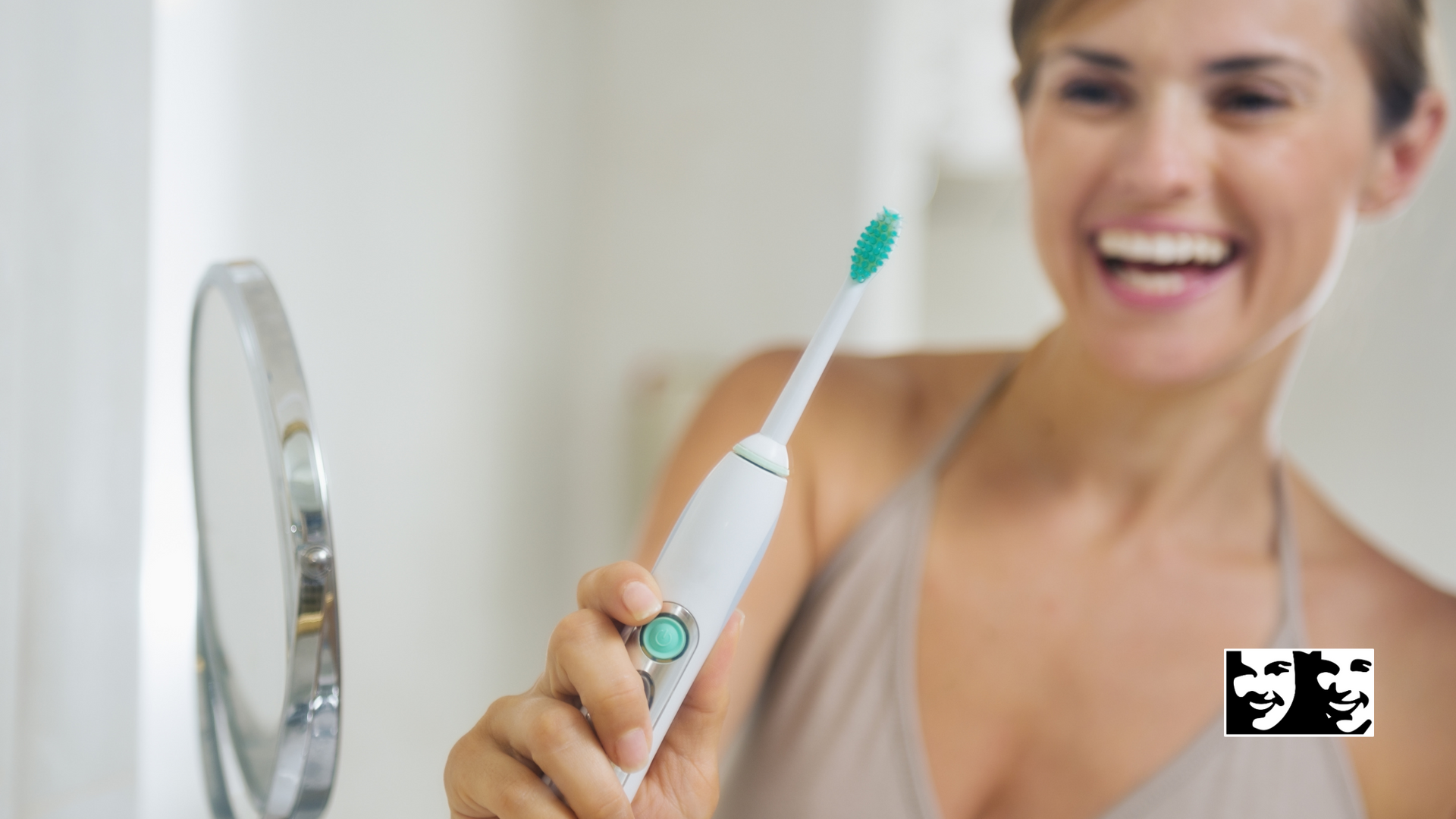 A woman is holding an electric toothbrush in front of a mirror.