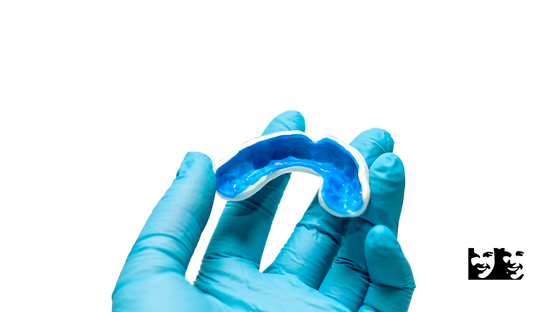A person wearing blue gloves is holding a blue mouth guard.