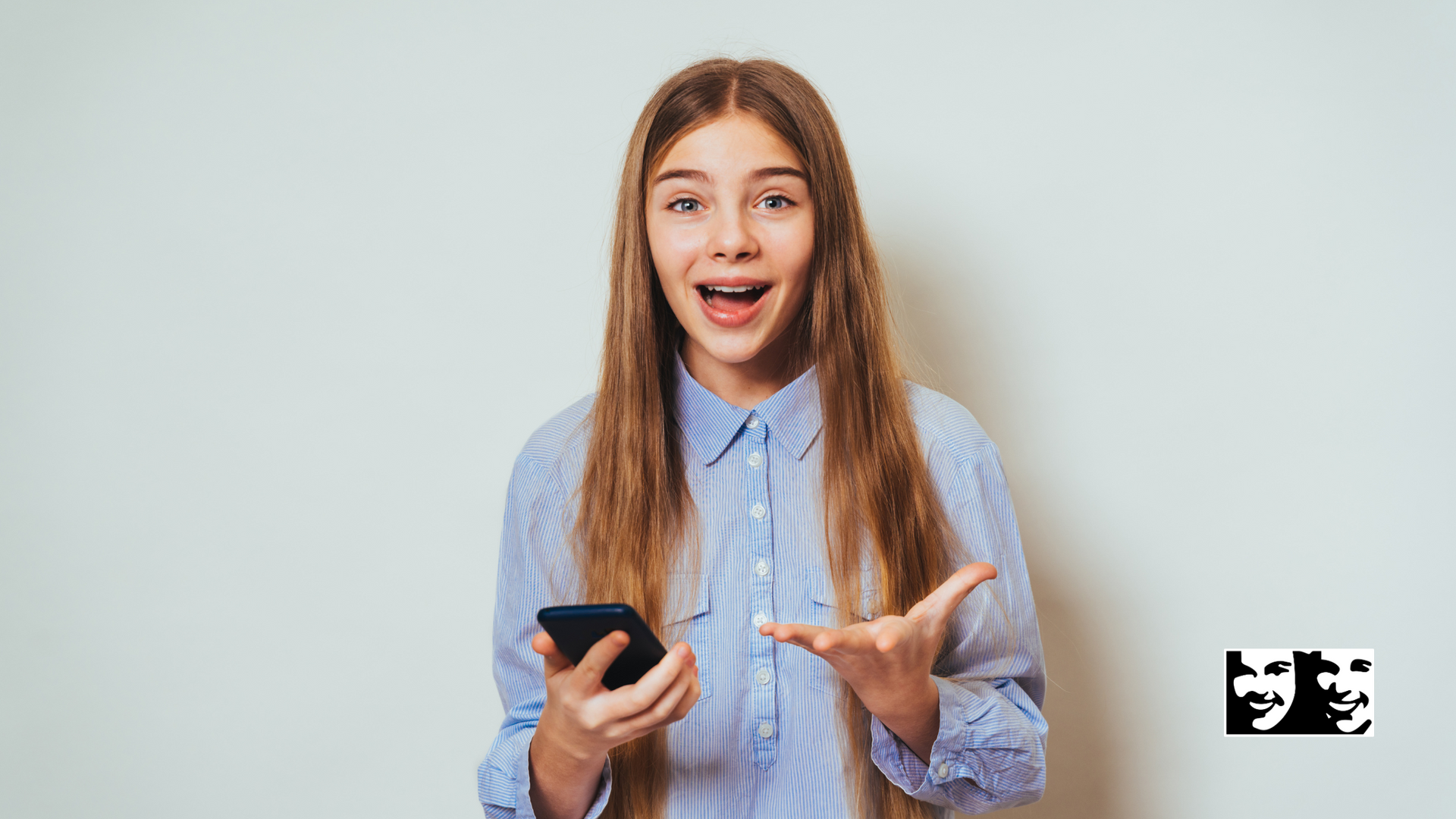 A young girl is holding a cell phone in her hand and making a surprised face.