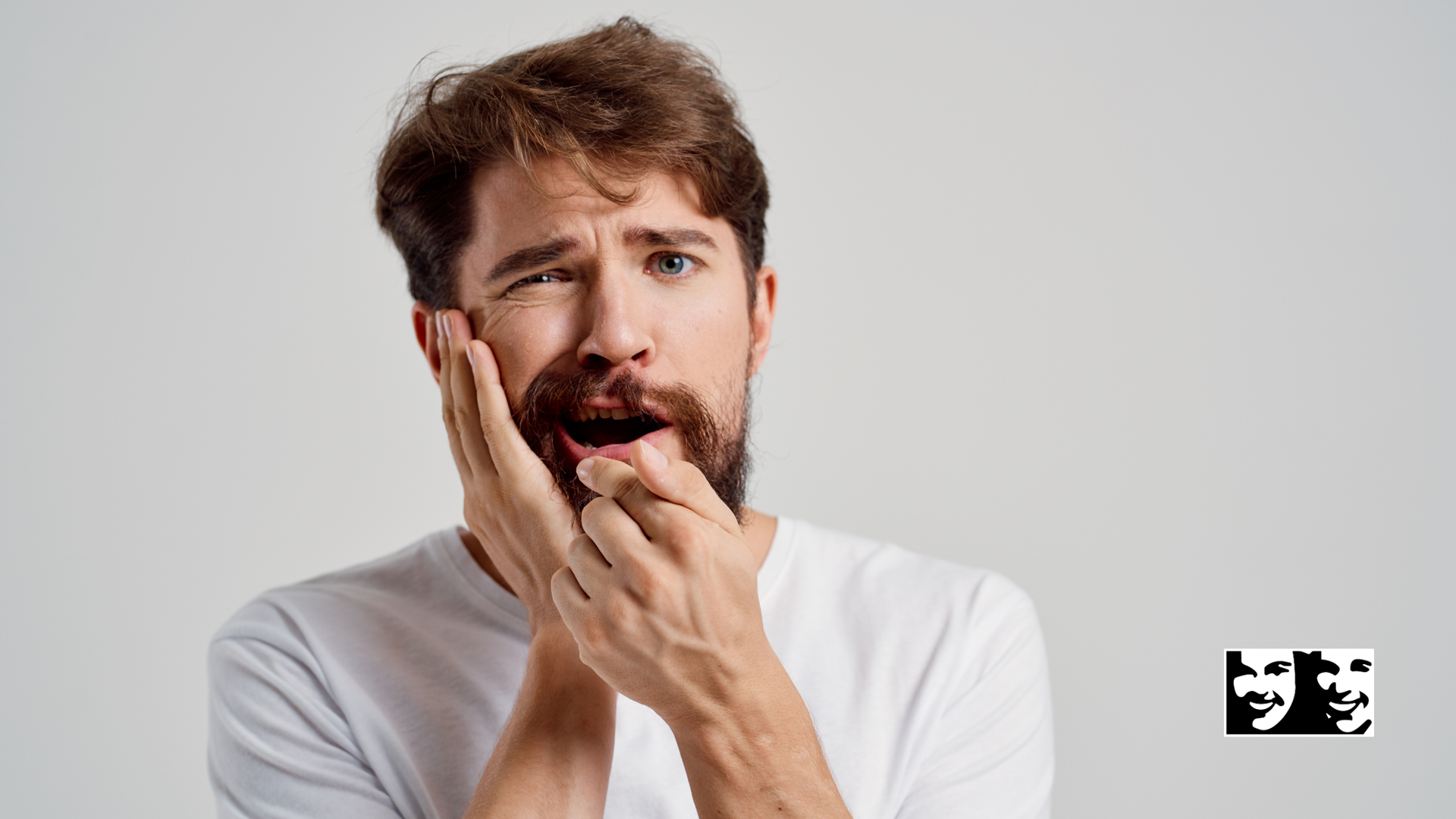 A man with a beard is covering his mouth with his hands.