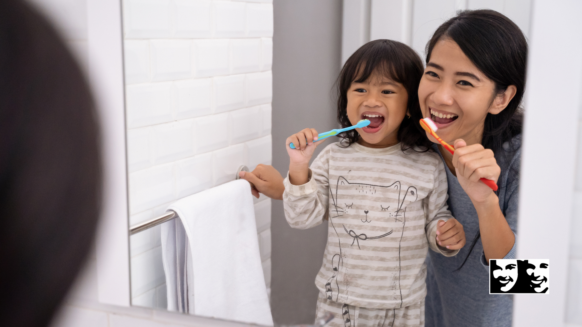 A woman and a child are brushing their teeth in front of a mirror.