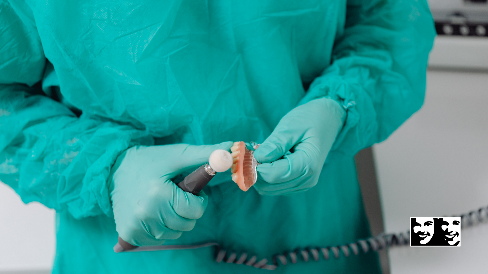 A surgeon in a green gown and gloves is holding a piece of meat.