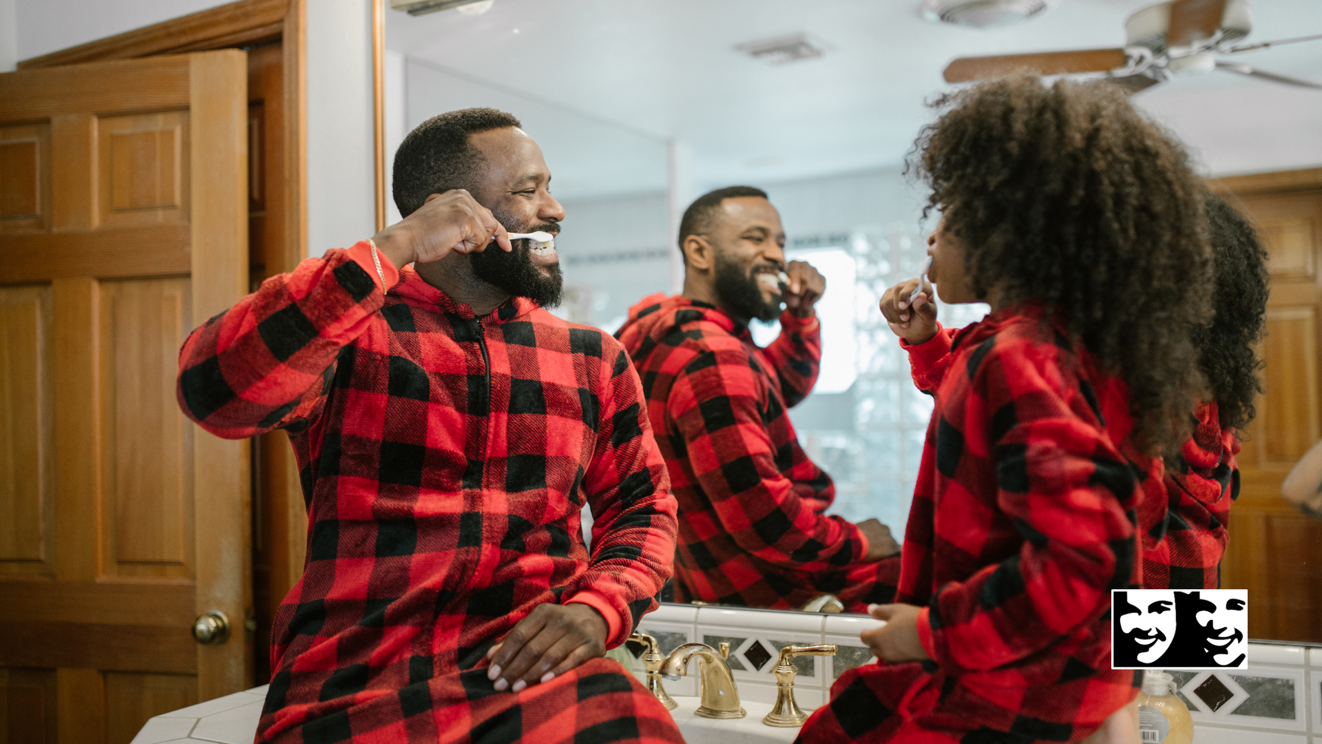 A man and a woman are brushing their teeth in front of a bathroom mirror.