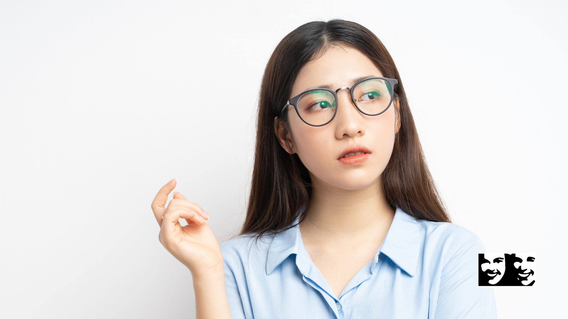 Woman with glasses looking away, hand raised. Pale blue shirt, white background.