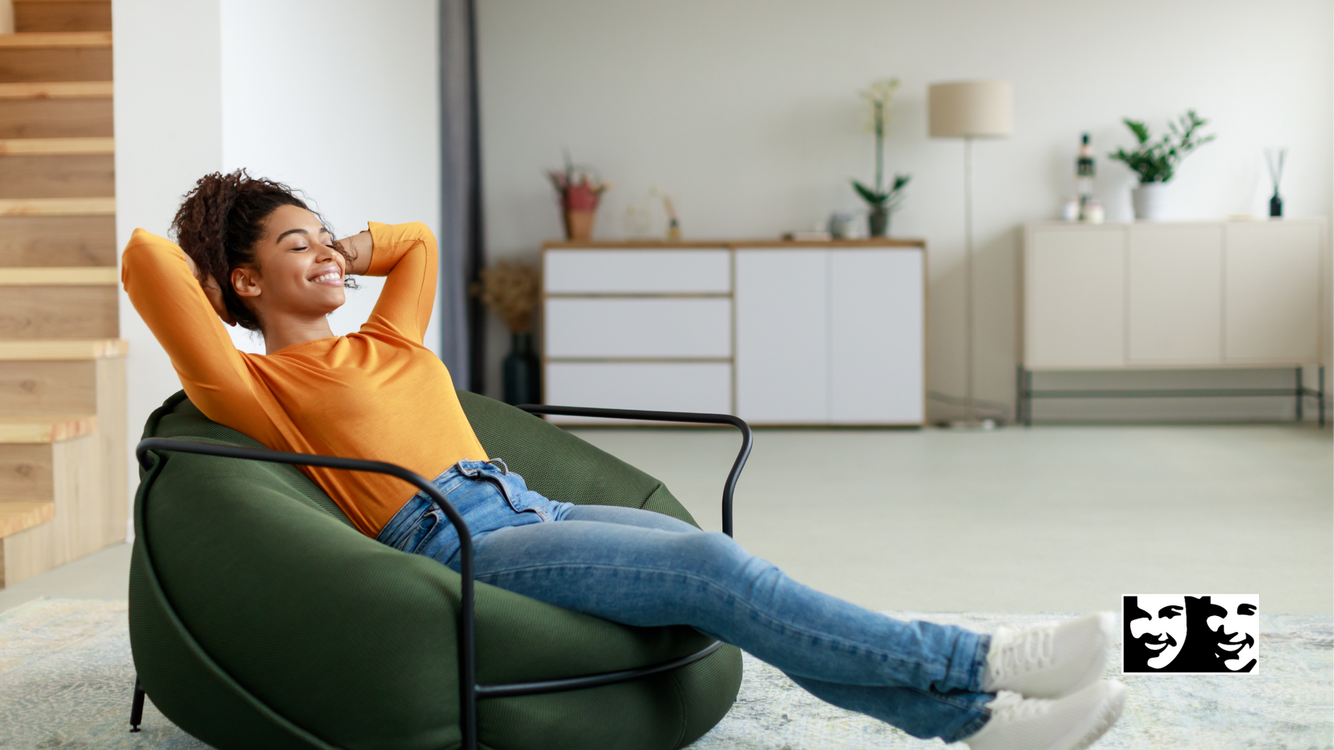Woman in orange shirt, blue jeans relaxing in green beanbag chair. Hands behind head, smiling. Living room setting.
