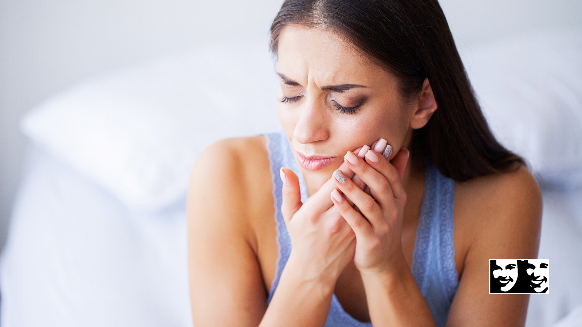 A woman is sitting on a bed with a toothache.