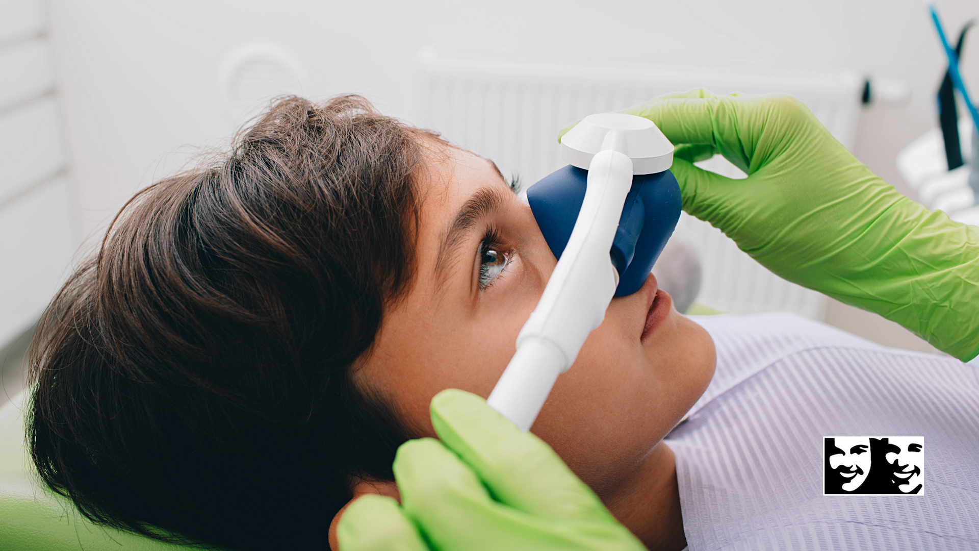 A young boy is laying in a dental chair with an oxygen mask on his nose.
