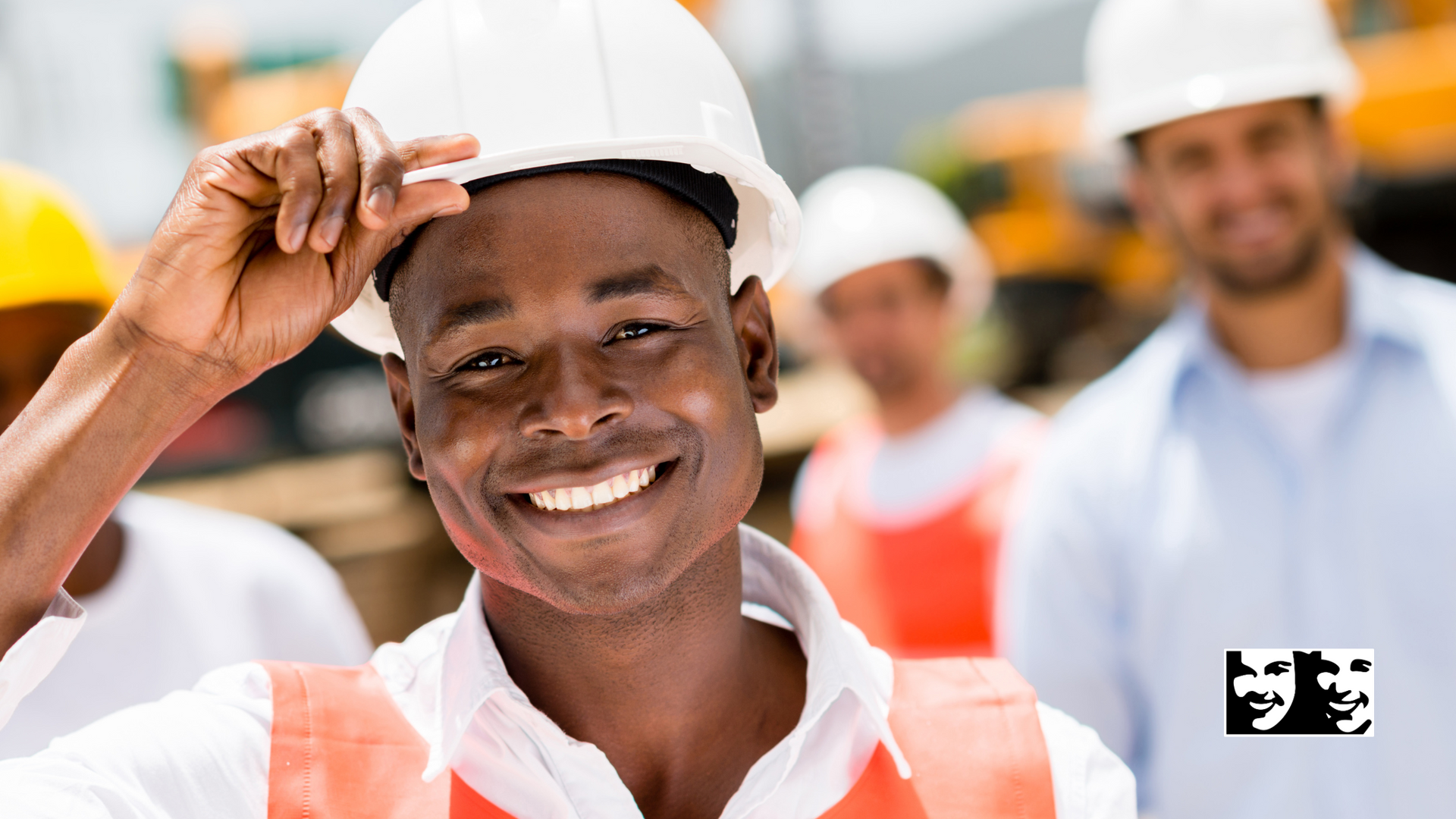 A man wearing a hard hat and an orange vest is smiling.
