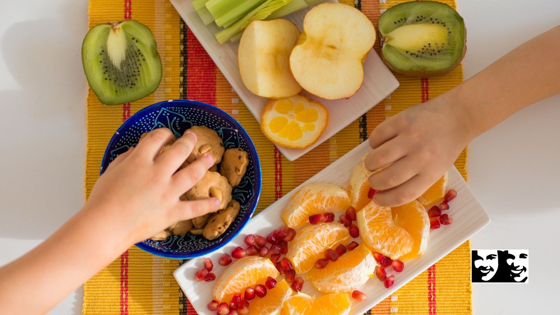 A child is reaching for a plate of fruit on a table.