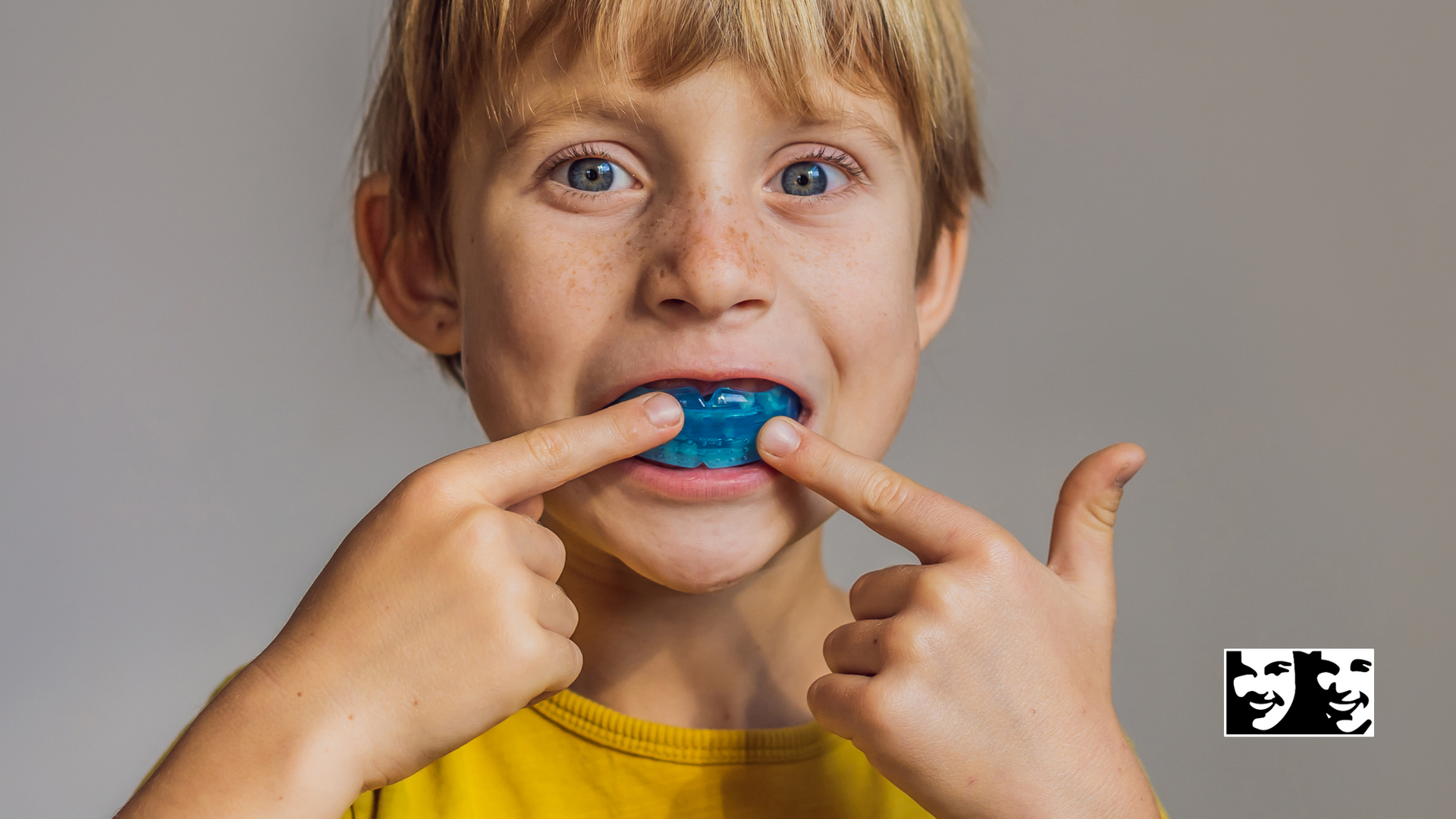 A young boy is wearing a blue mouth guard.