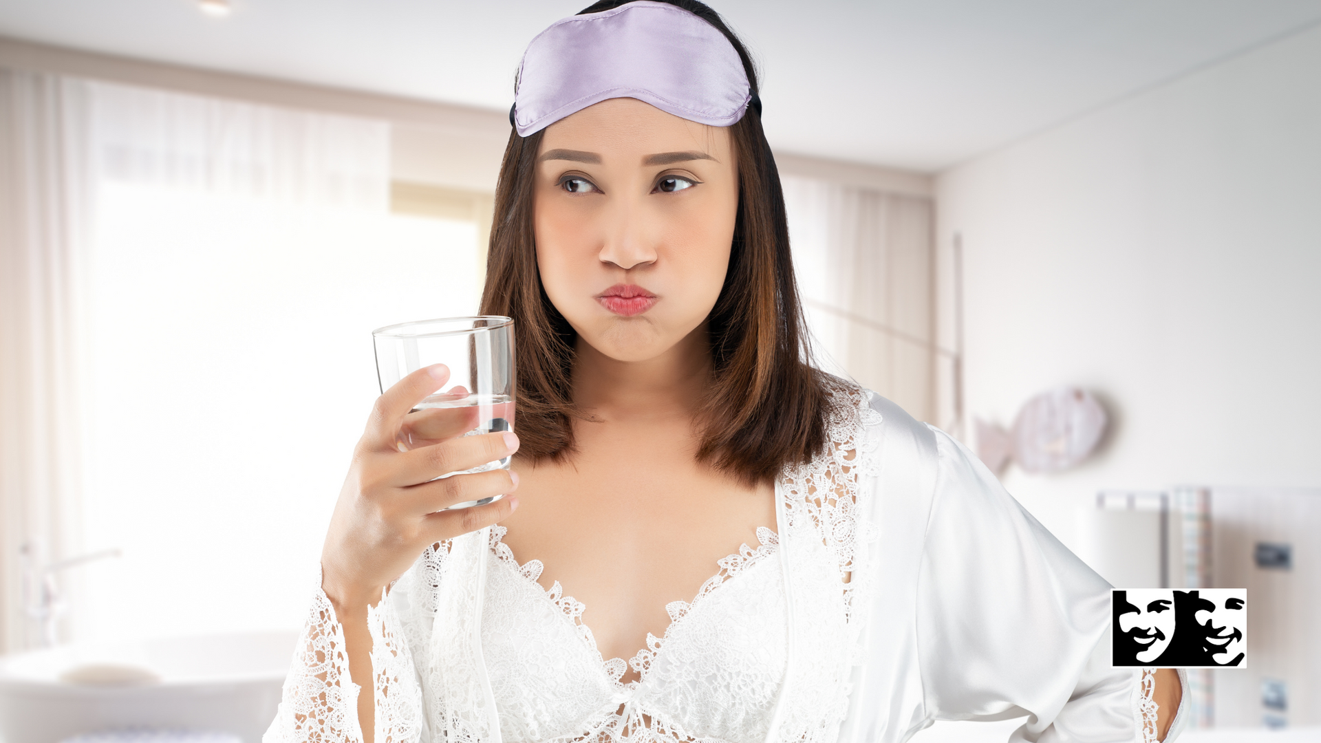 A woman wearing a sleep mask is drinking a glass of water.