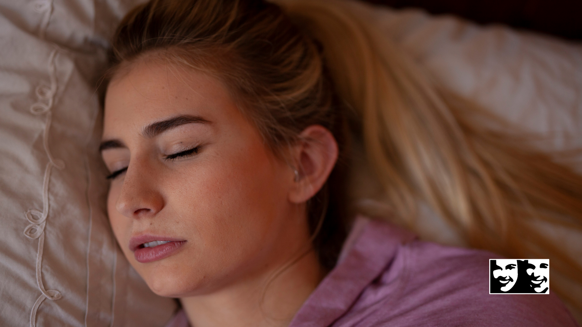 A woman is sleeping on a bed with her eyes closed.