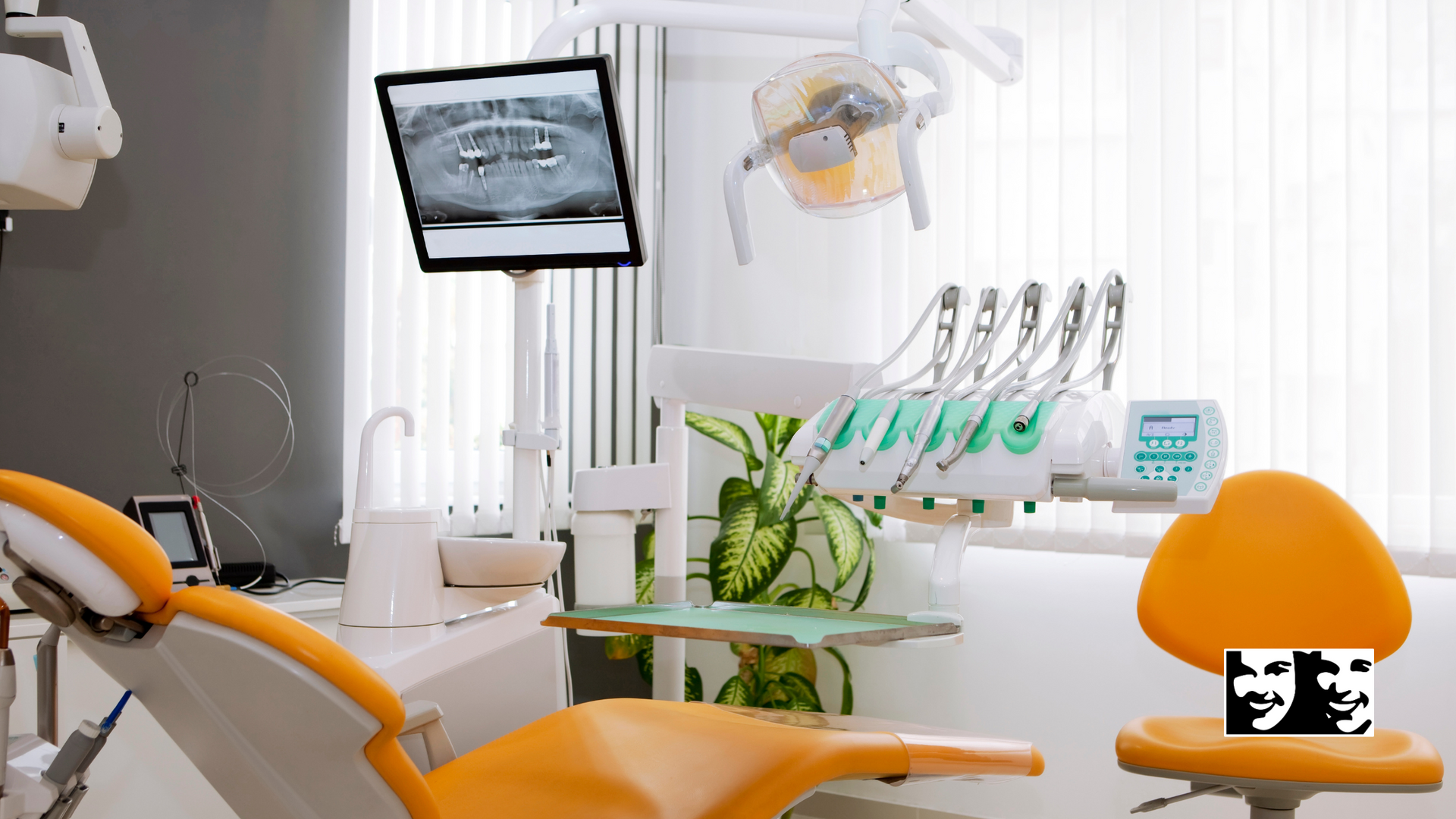 A dental office with an orange chair and a monitor