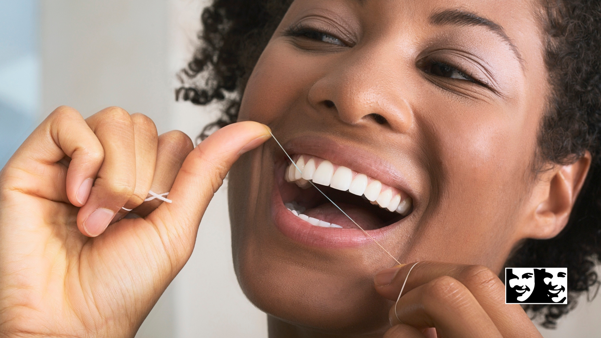Woman flossing teeth and smiling in close-up