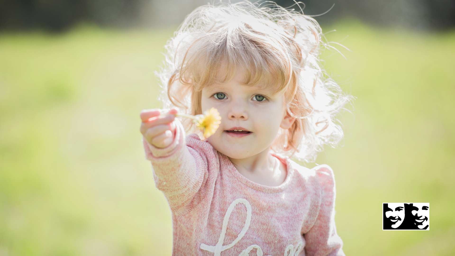 A little girl is holding a flower in her hand.