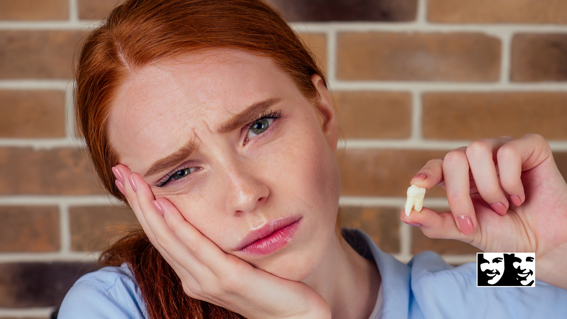 A woman with red hair is holding a tooth in her hand.