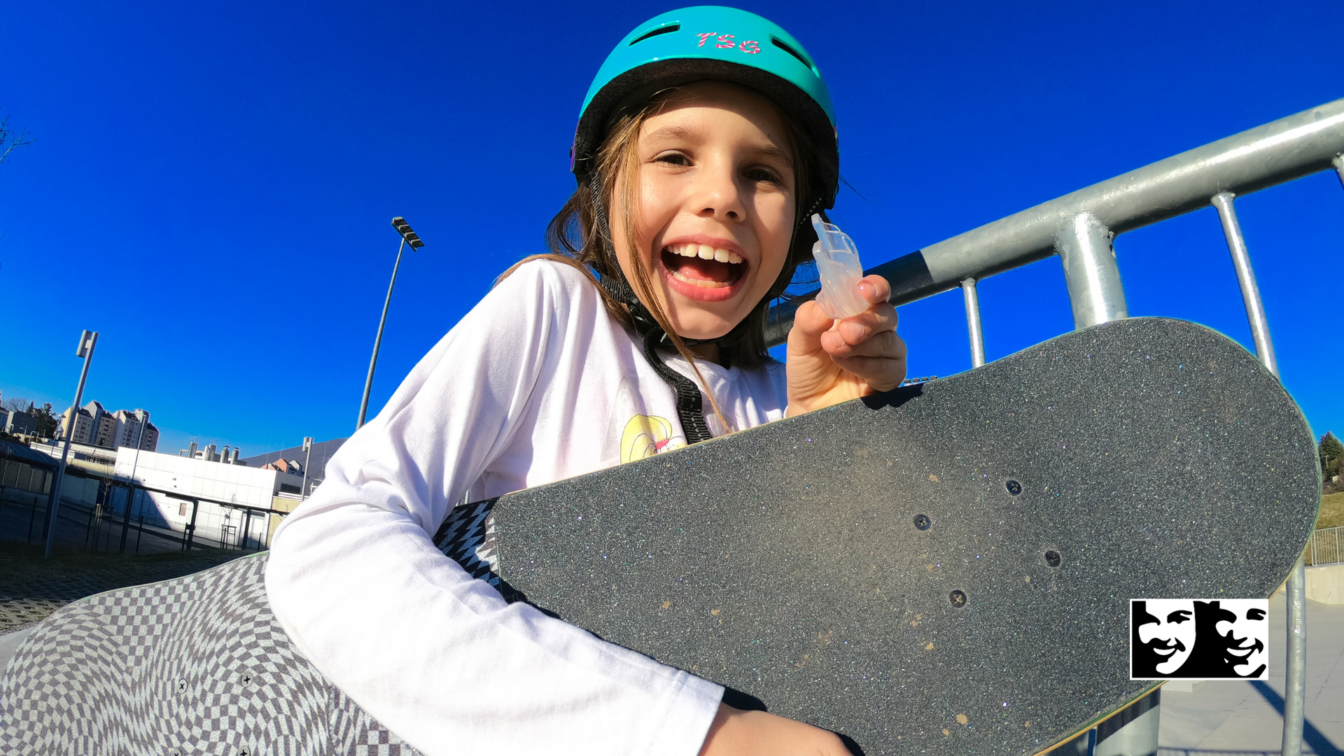 A young girl wearing a helmet is holding a skateboard.