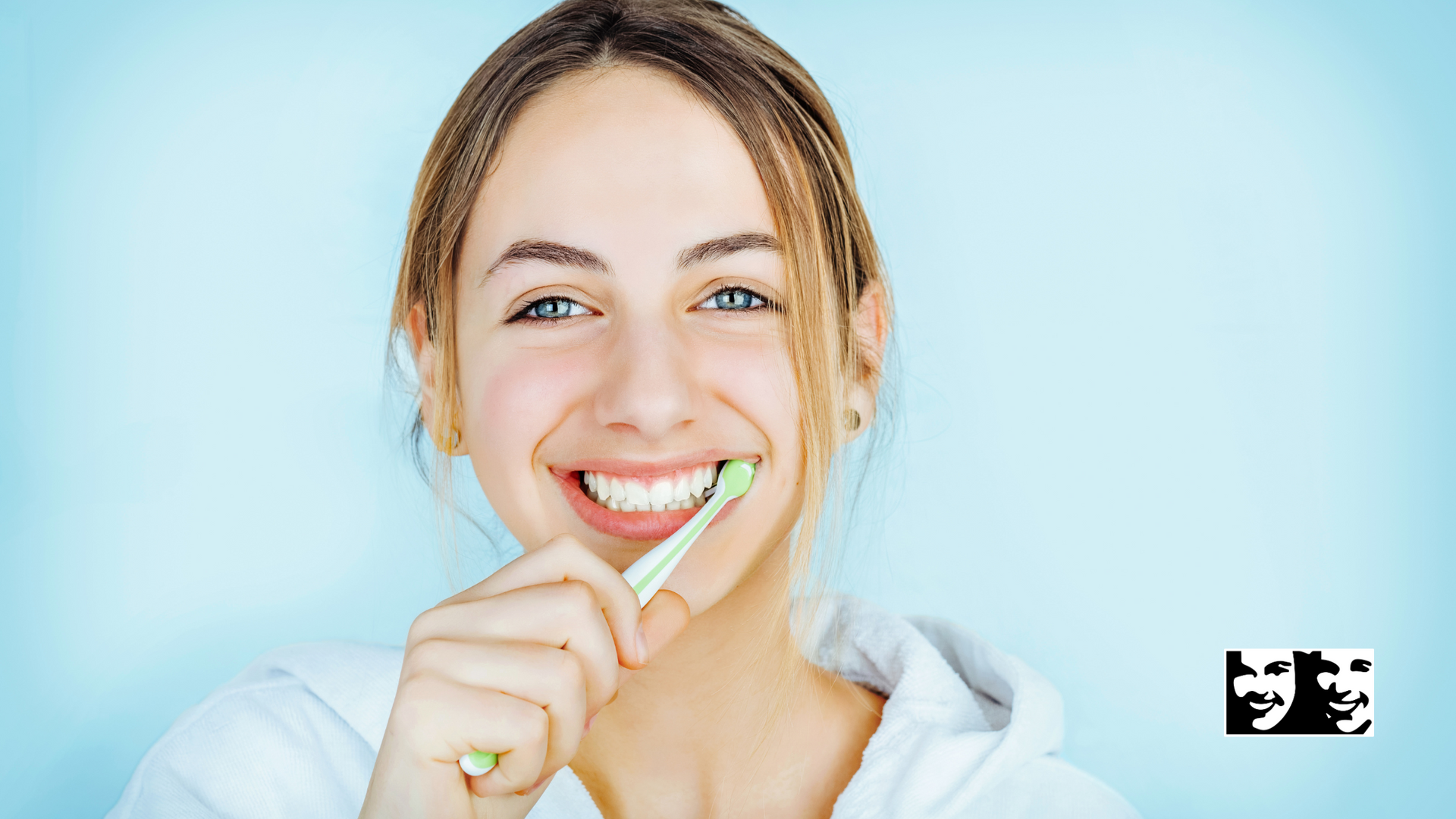 Woman brushing teeth, smiling widely, against a light blue background.
