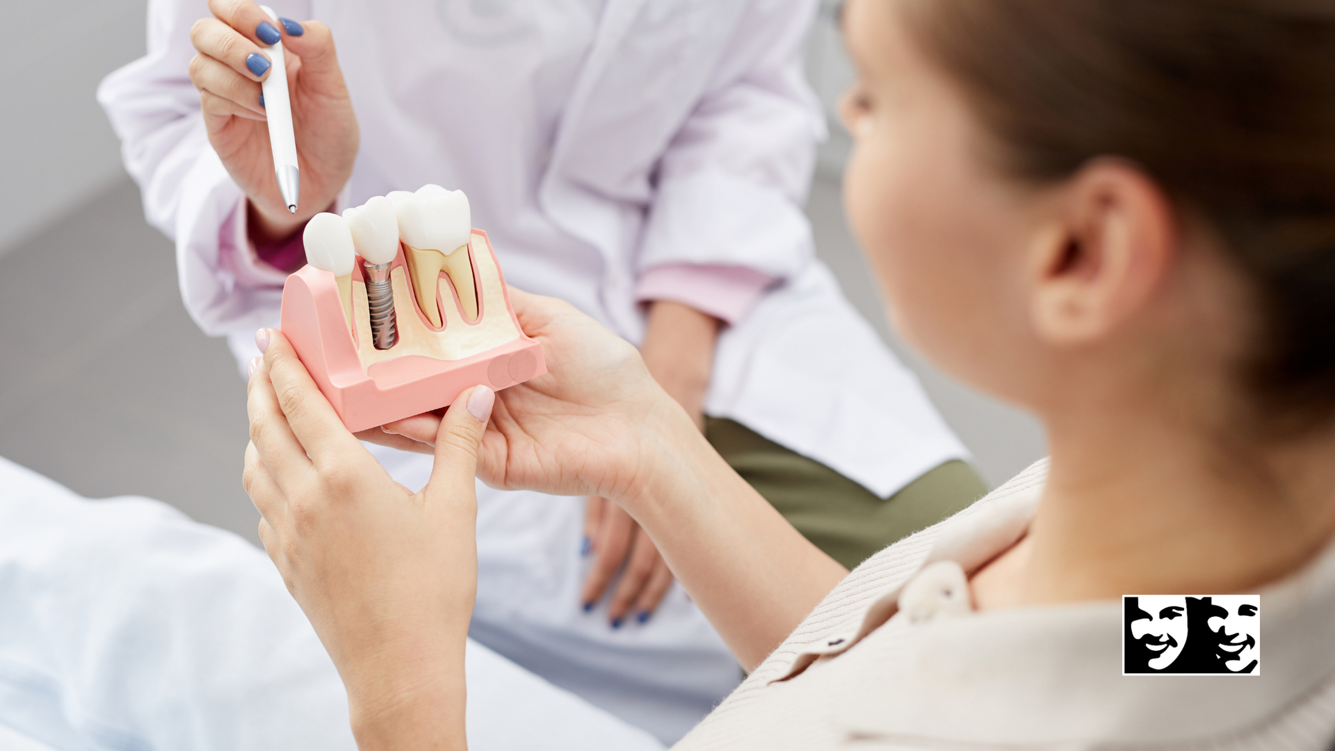 A woman is sitting in a dental chair looking at a model of teeth.
