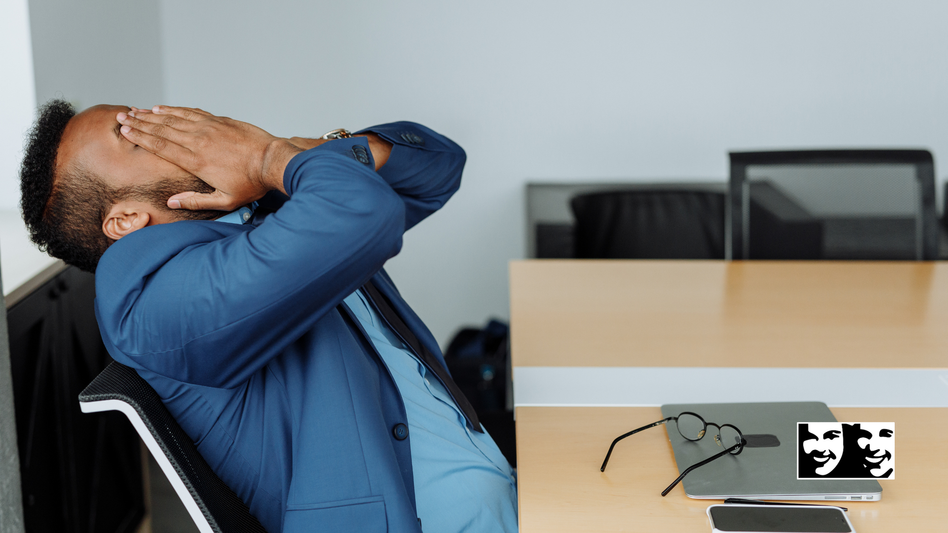 A man is sitting at a desk with his head in his hands.