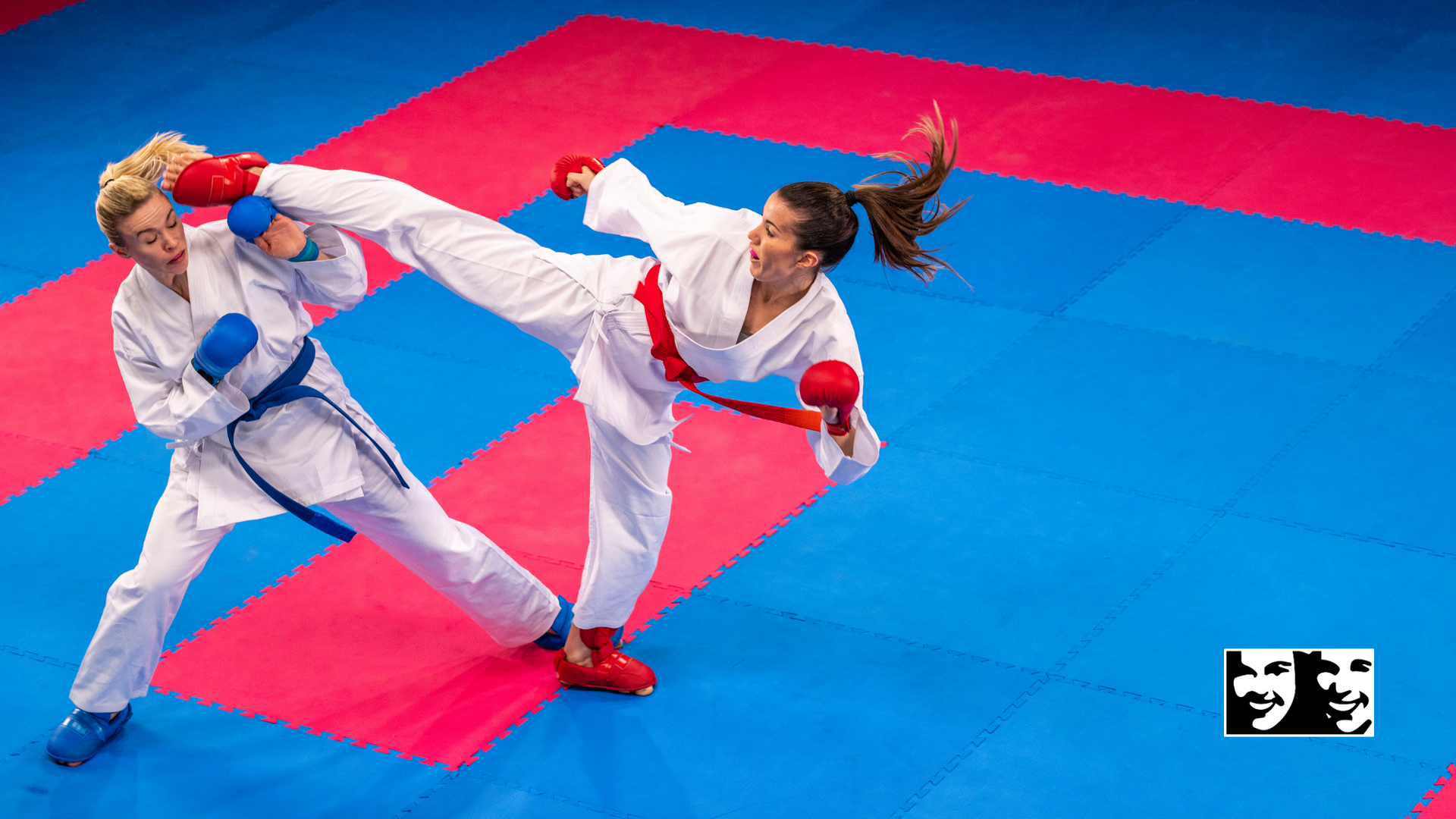 Two karate fighters are fighting on a blue and red mat.