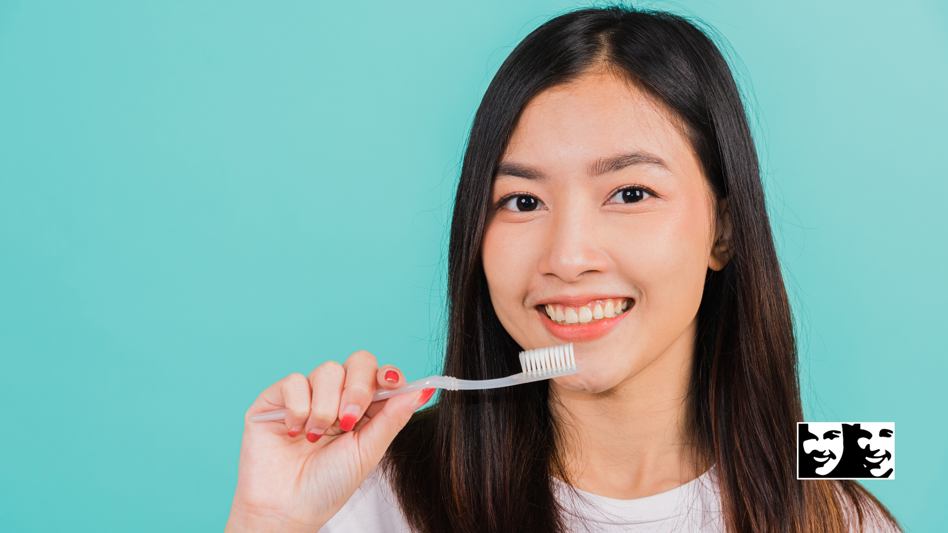 A woman is brushing her teeth with a toothbrush and smiling.
