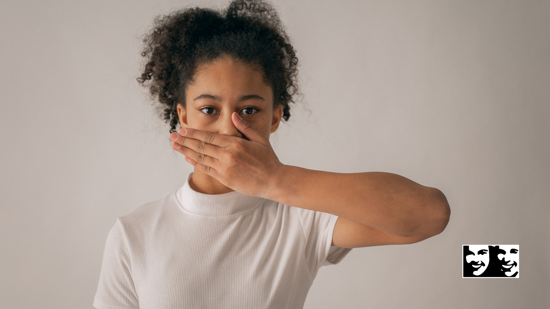 A young girl is covering her mouth with her hand.