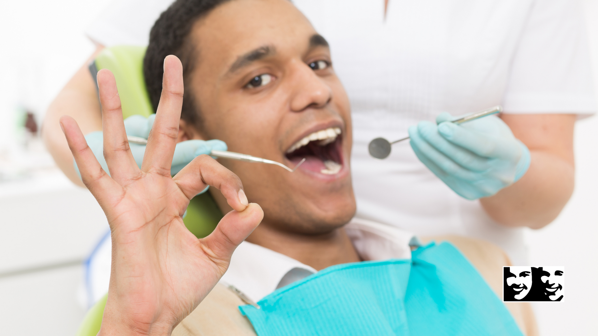 A man is sitting in a dental chair giving an okay sign.
