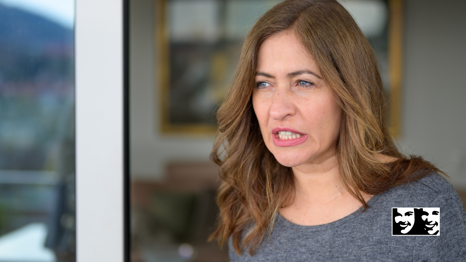 A woman is standing in front of a window making a funny face.