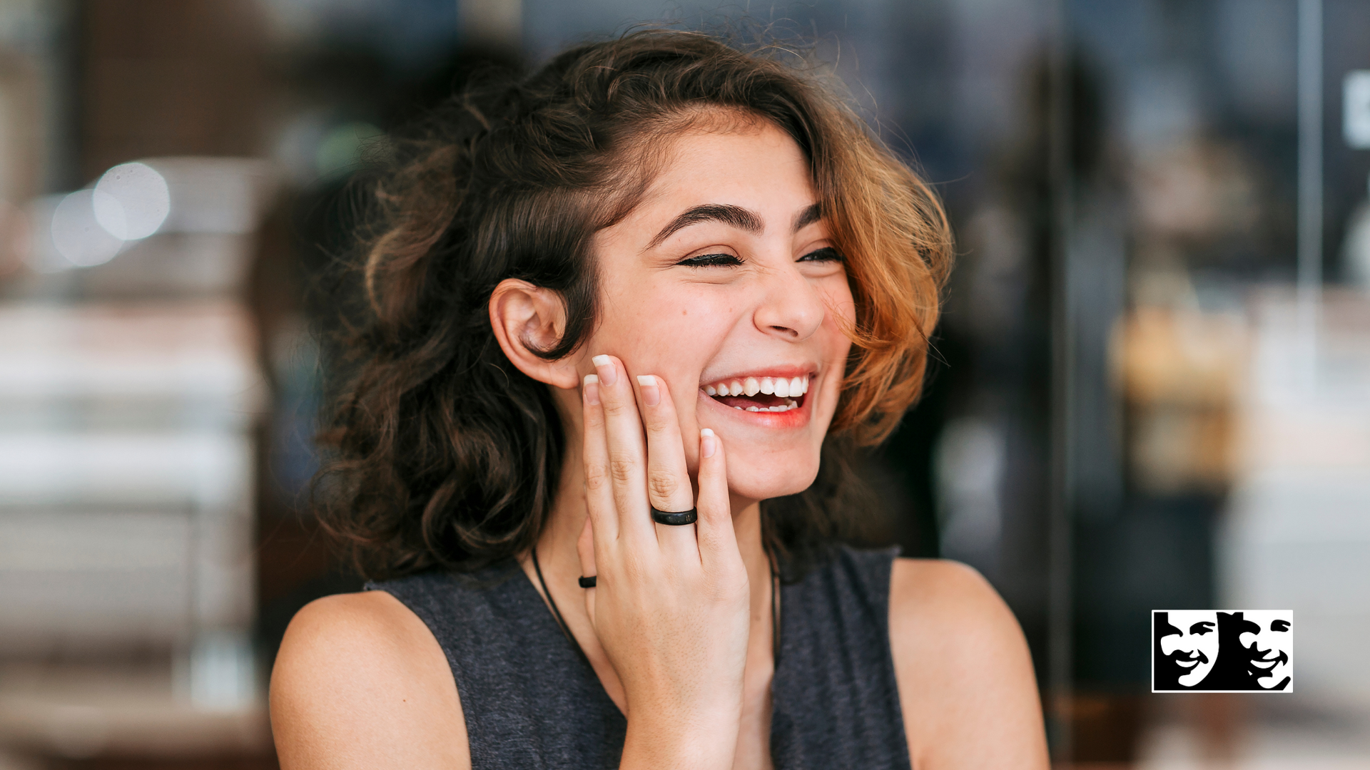 A woman is laughing with her hand on her face.