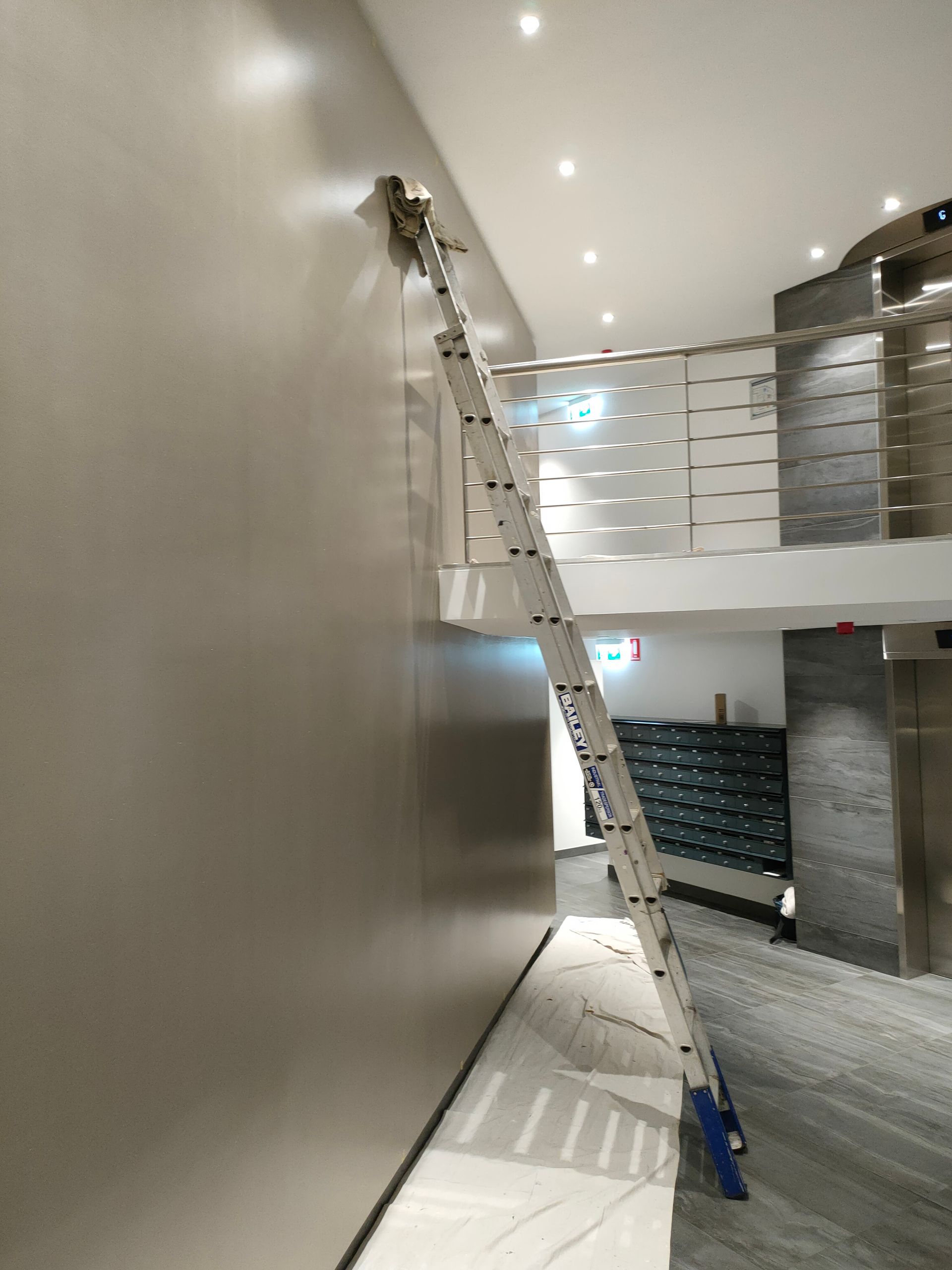 A Man is Painting a Building With a Roller — Timeless Painting In Umina Beach, NSW