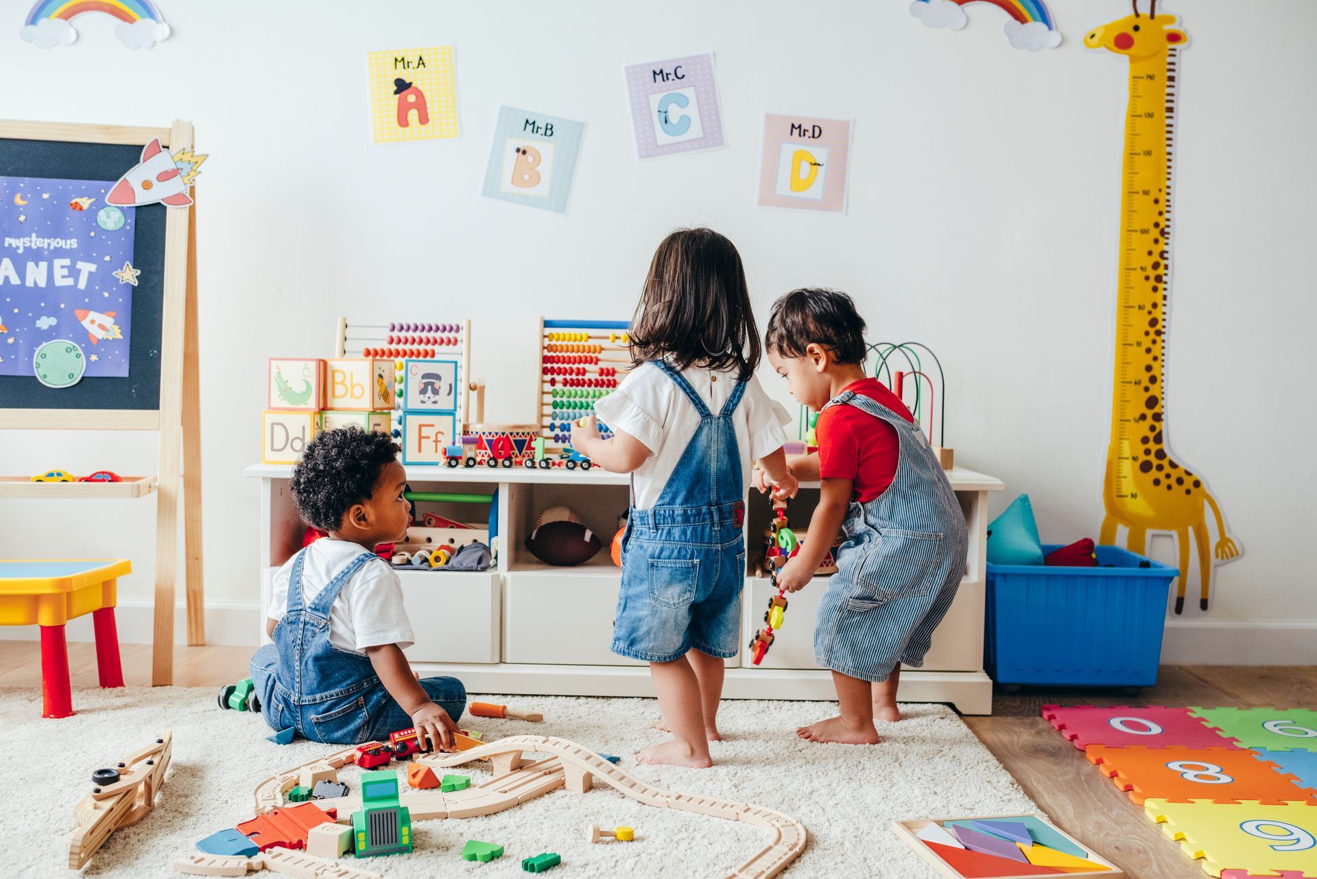 Toddlers playing with wooden toys and colorful blocks in a bright classroom