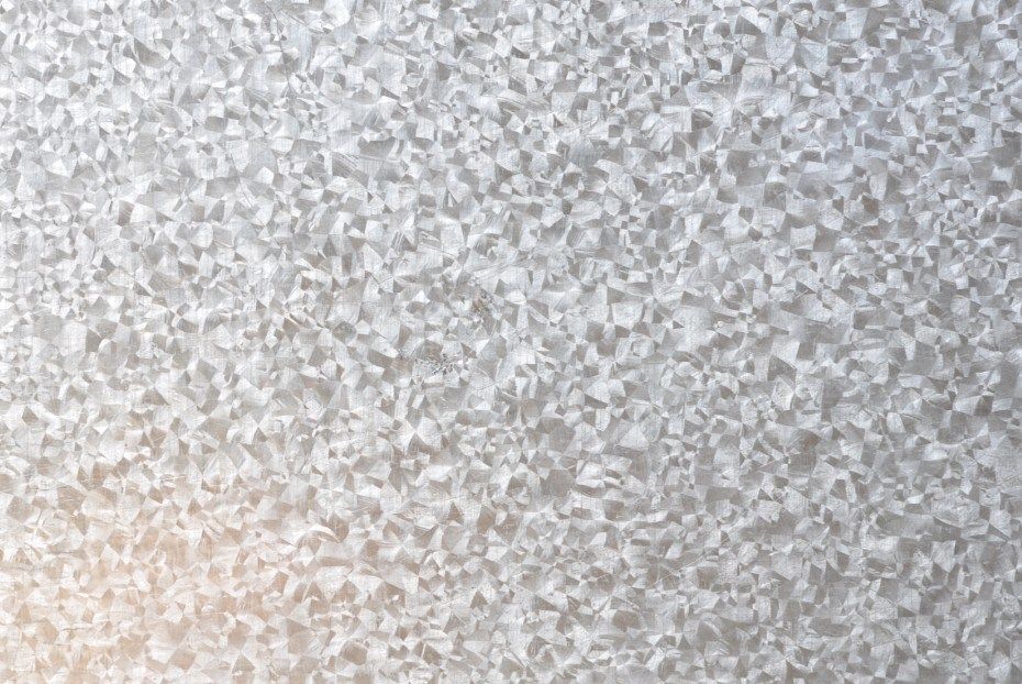Vue rapprochée de l'acier galvanisé, montrant un motif texturé et cristallin.