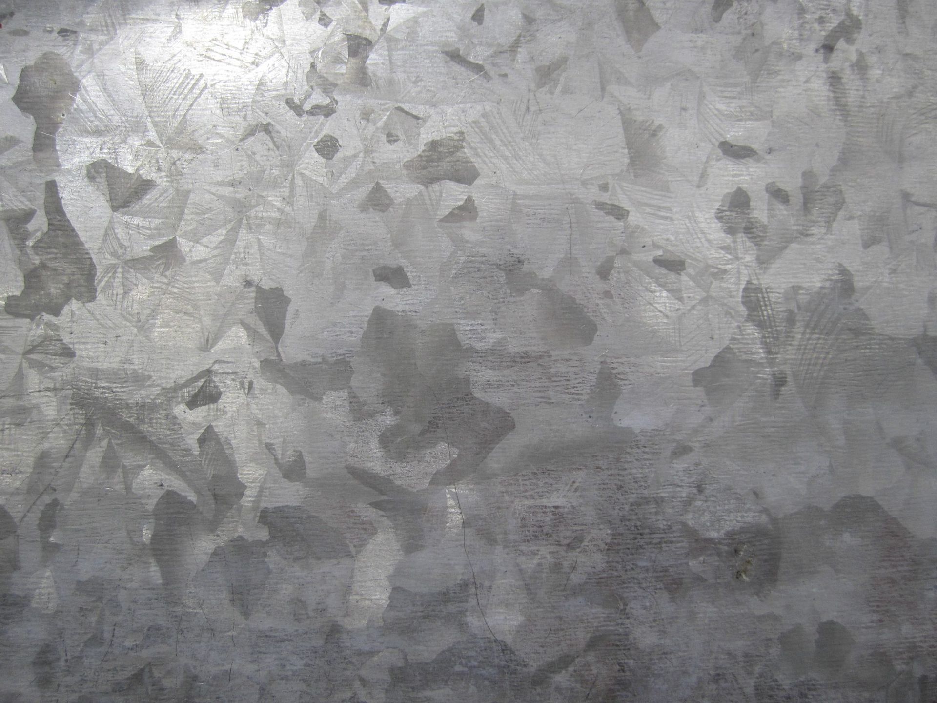 Vue rapprochée d'une surface en acier galvanisé avec des motifs cristallins visibles, dans des tons de gris.