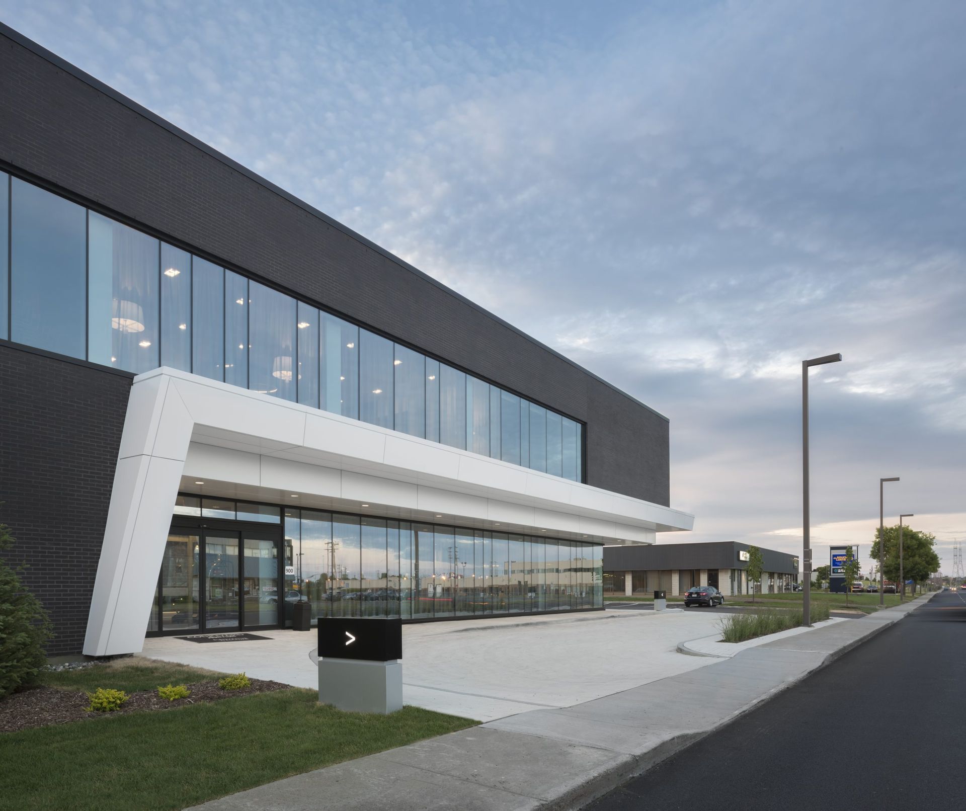 Immeuble de bureaux moderne avec façade noire, grandes fenêtres et accents géométriques blancs.