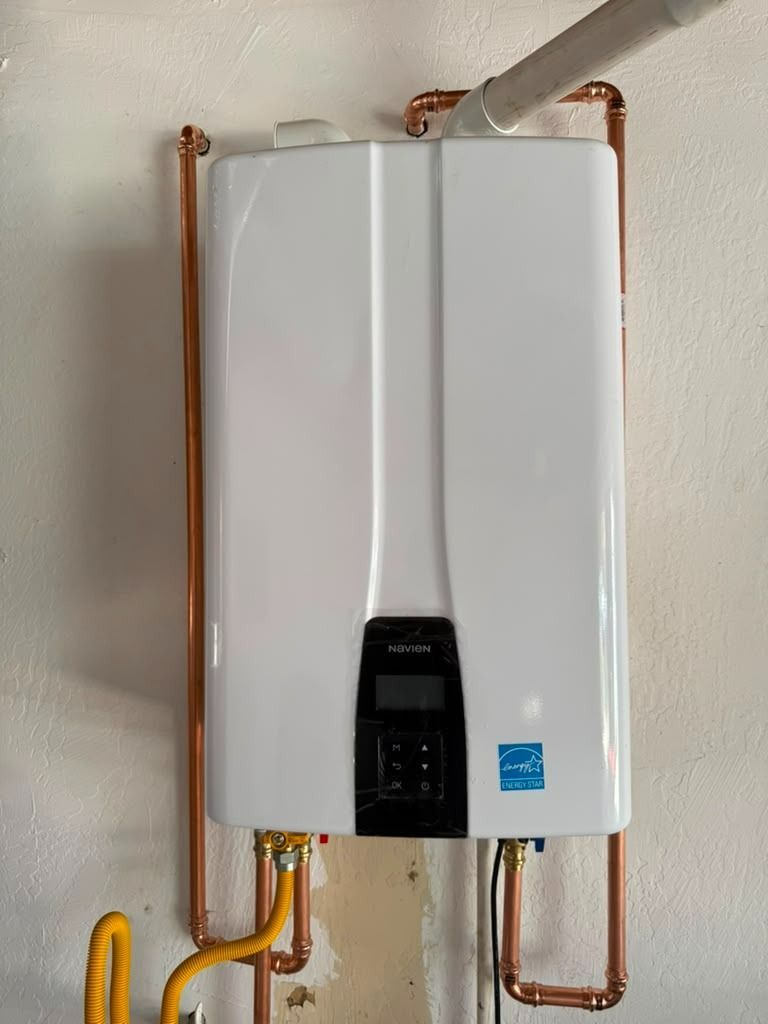 Wall-mounted white water heater with exposed copper pipes and a small control panel.