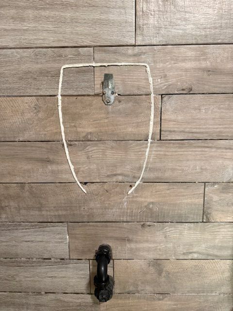 Two metal wall hooks on a wood plank wall, one silver above and one black below