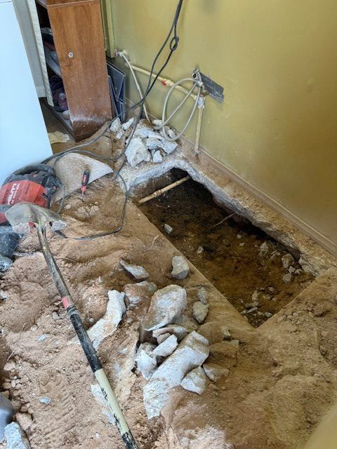Damaged floor with exposed subfloor, debris, and electrical wires beside a wall opening