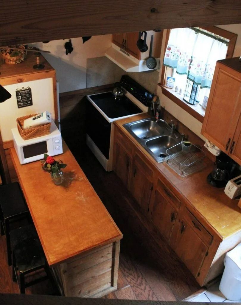 Compact kitchen with wood counters, sink, stove, and a small table by a window