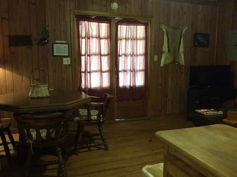 Wood-paneled living room with table, chairs, curtained door, and TV.