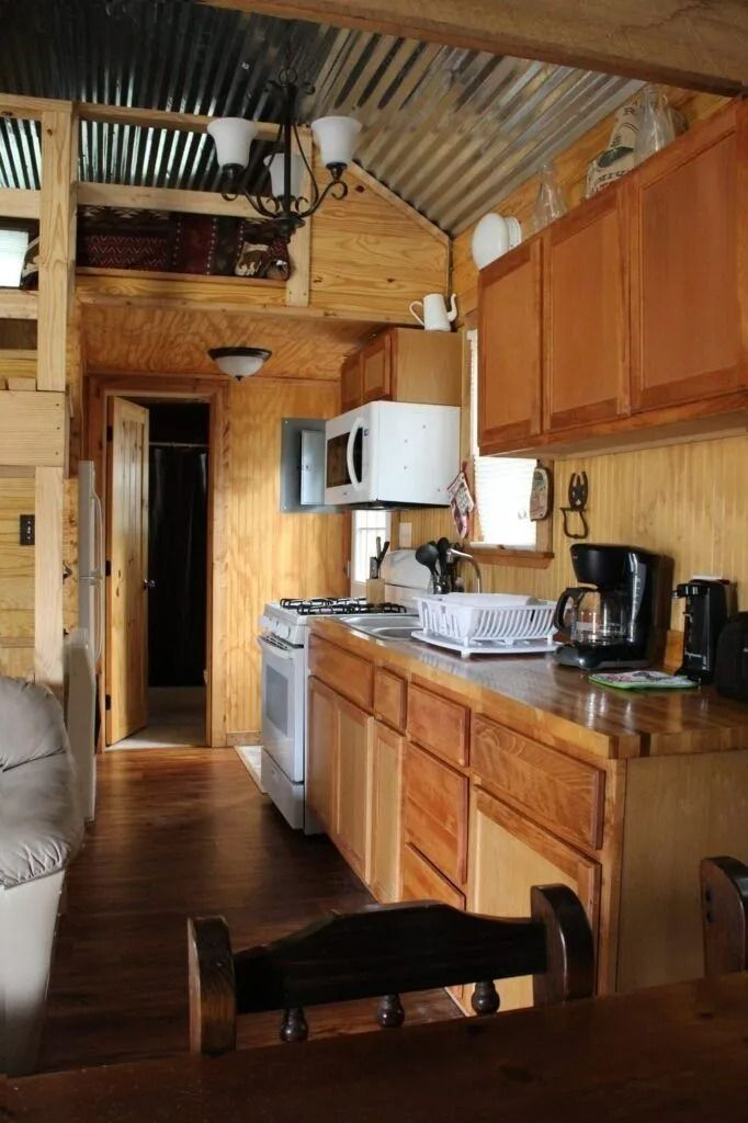 Rustic kitchen with wood cabinets, white appliances, and a dark table in the foreground