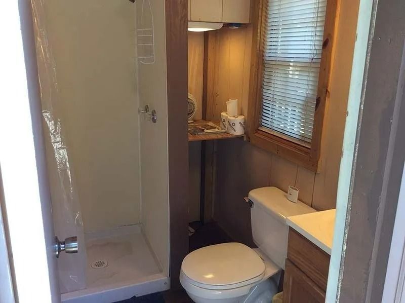 Small bathroom with shower, toilet, sink, and window blinds.