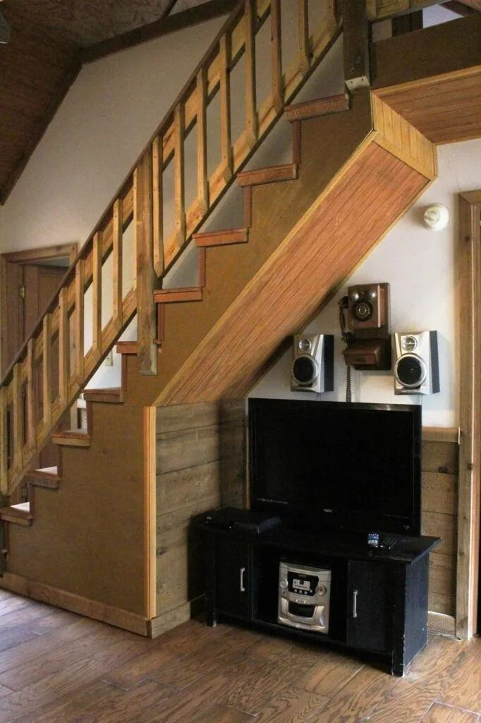 Loft staircase over a TV and stereo setup in a small living room.
