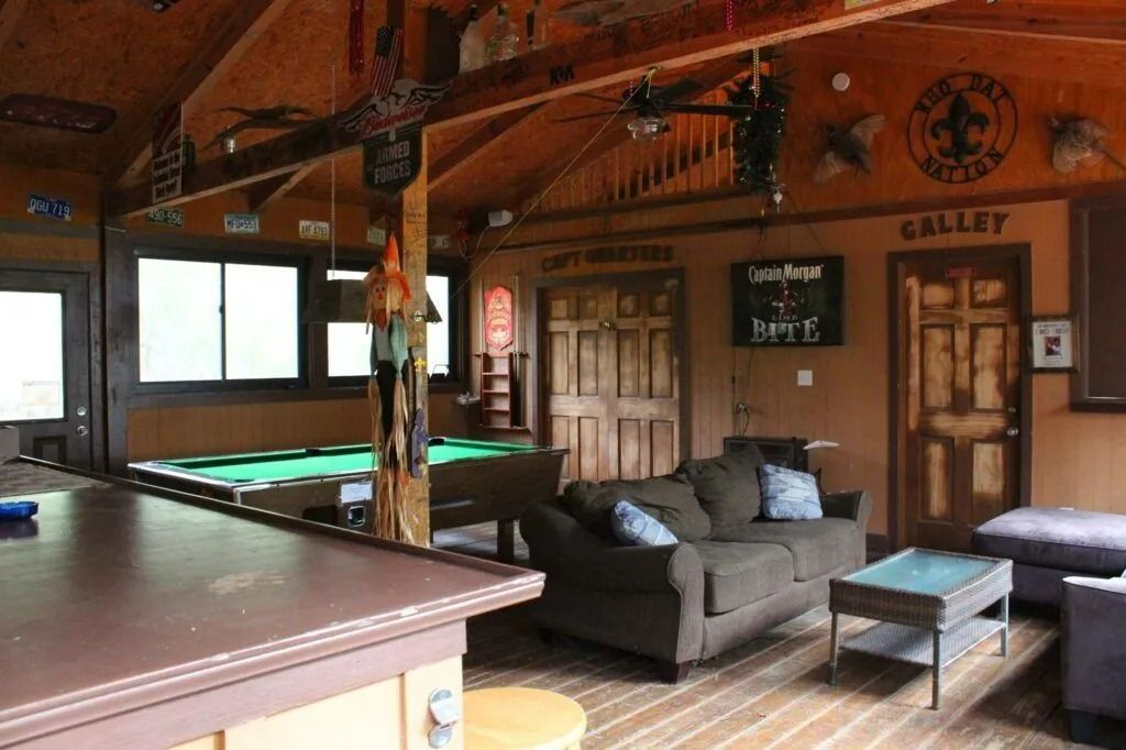 Wood-paneled game room with pool table, sectional sofa, and bar counter in the foreground